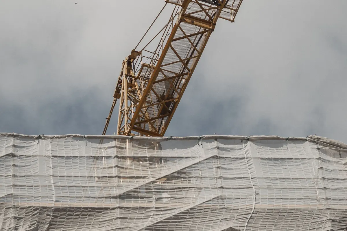 Block under construction with a tower crane, illustrative